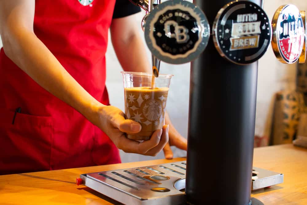 image of barista pouring nitro coffee from tap into glass for the post cold brew vs nitro cold brew 